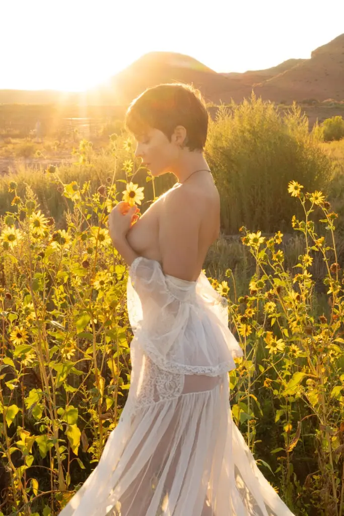 Sunrise photo model in a white sheer gown in a field of yellow flowers, model has short brown hair, profile perspective photography